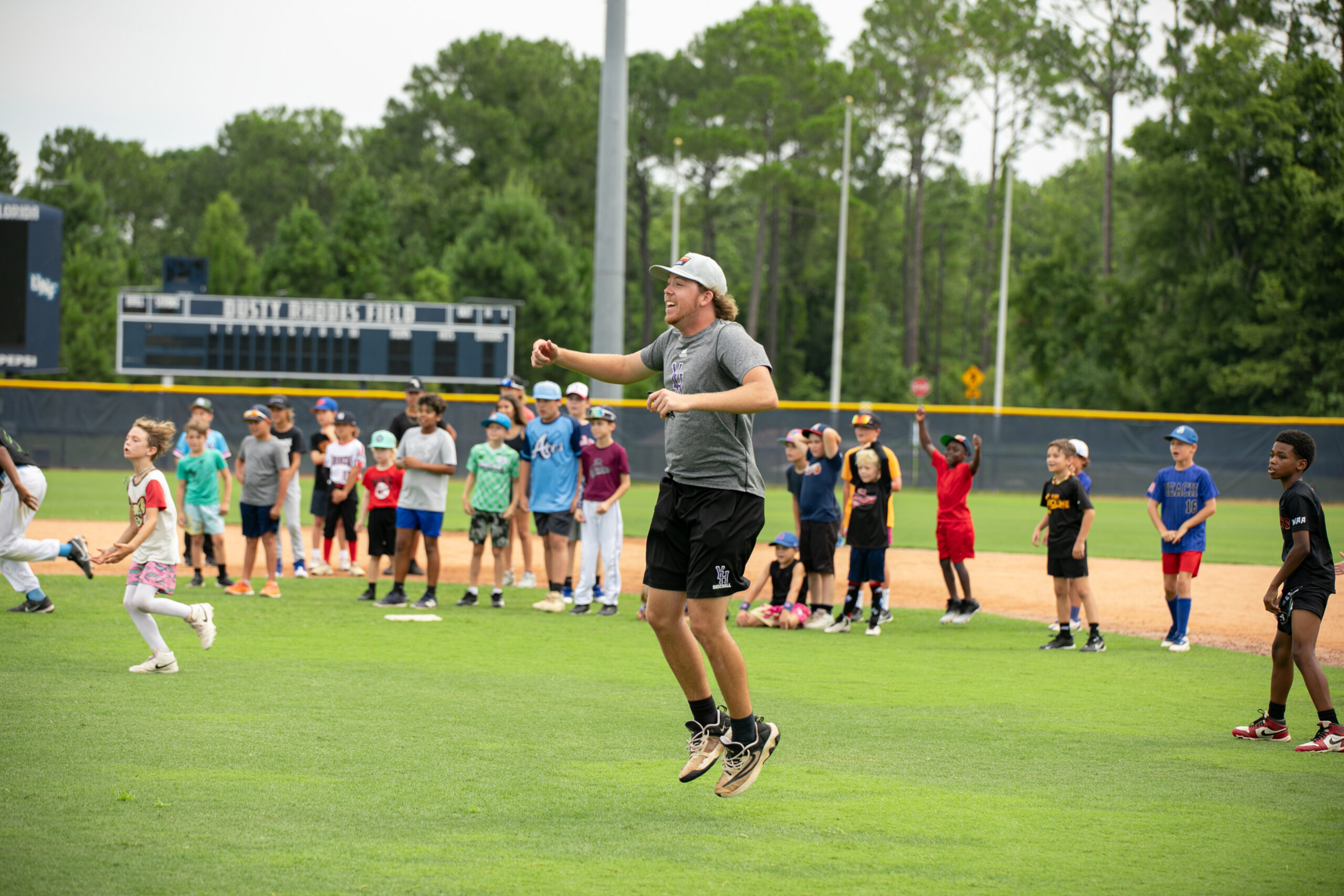 Instructor teaching UNF Baseball Camp in Jacksonville Florida. Jumping up and down on the field with campers aged 6-13